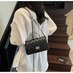 Quilted black leather flap bag with silver chain strap shown worn by a model