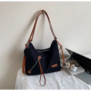 Detail of black tote bag with brown straps, silver zippers and small matching round pouch