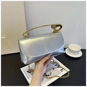 Détail du sac argenté avec poignée épingle de sûreté dorée et finition brillante