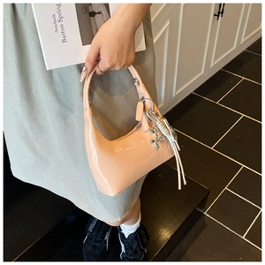 Detail of peach patent leather bucket bag with silver charm and stylish long tassels