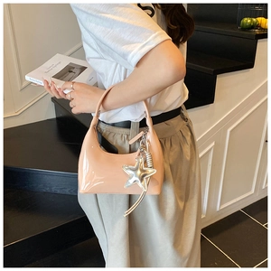 Detail of glossy patent leather handbag in soft pink with a silver star charm