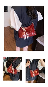 Close-up of wine red glossy patent leather tote bag with stylish tassel accessory detail