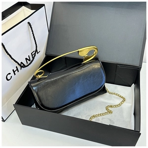 Détail d'un sac en cuir noir brillant avec une grande poignée épingle dorée et chaîne
