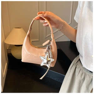 Detail of pink-beige patent leather bucket bag with silver star charm and glossy finish