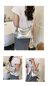 Macro detail of silver metallic tote bag with tassel charm and sleek metal logo plate