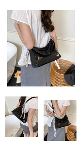 Detail view of black glossy tote bag with silver M logo and polka dot silk scarf charm