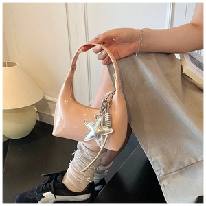 Detail shot of nude patent leather mini bag with silver star charm and spiral accent