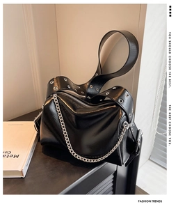 Détail d'un sac cabas en cuir noir brillant avec chaîne argentée et bandoulière