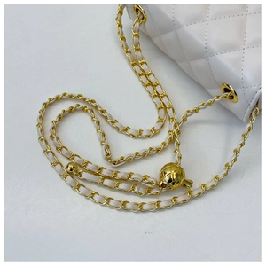 Détail du sac matelassé blanc avec bandoulière à chaîne et boule dorée réglable