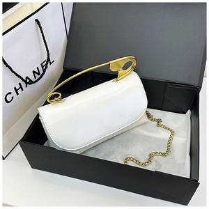 Détail d'un sac en cuir blanc avec une poignée unique en forme de grande épingle dorée