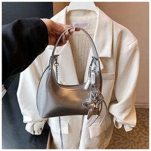 Detail of silver metallic bucket bag with crescent shape and star charm accessory
