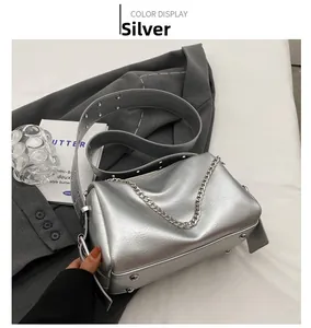 Vue détaillée du sac cylindrique argenté avec chaîne métallique et bandoulière sur costume