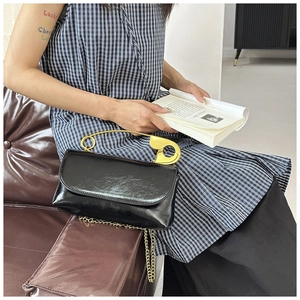 Détail du sac en cuir verni noir brillant avec poignée dorée en forme de grande épingle