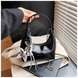 Detail of glossy black patent leather bucket bag with silver star pendant and chain strap