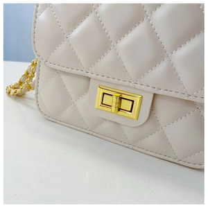 Gros plan du fermoir doré sur un sac à main beige à motif de losanges matelassés