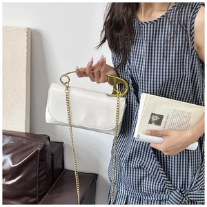 Détail du sac bandoulière en cuir blanc avec poignée épingle à nourrice dorée et chaîne