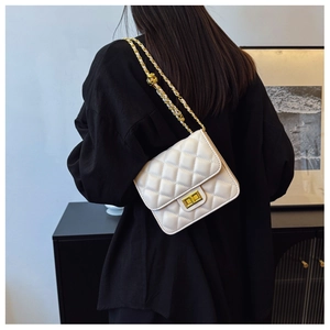 Détail du sac à bandoulière matelassé beige avec chaîne dorée et fermoir rotatif