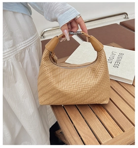 Detail of camel woven leather texture and silver buckle on chic crescent handbag