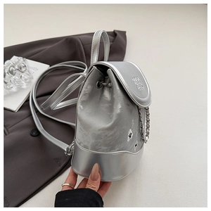 Detailed shot of silver velvet mini backpack with metallic chain and embossed logo flap