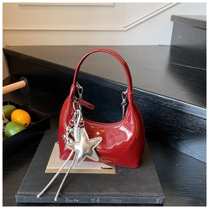 Detail view of red glossy patent leather handbag with a silver star charm accessory