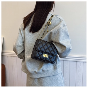 Détail d'un mini sac matelassé noir avec chaîne dorée porté par un mannequin de dos