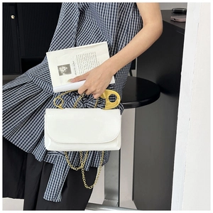 Détail d'un sac bandoulière blanc brillant avec poignée épingle à nourrice dorée