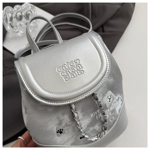 Close-up of silver mini backpack showing embroidery detail and metal chain straps