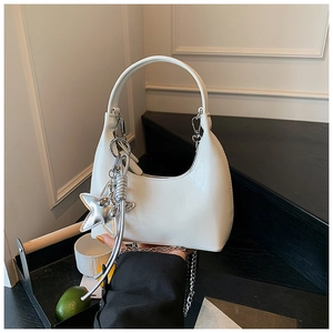 Detail of white glossy patent leather hobo bag with silver chain and star charm