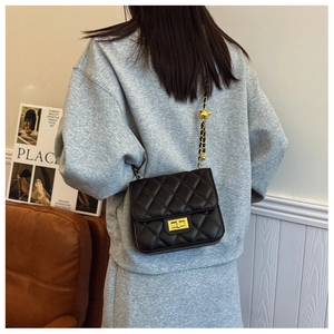 Détail d'un sac bandoulière matelassé noir avec chaîne dorée et boucle à boule
