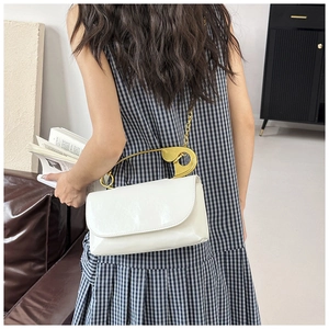Vue détaillée du sac en cuir blanc avec grande épingle de sûreté dorée et chaîne