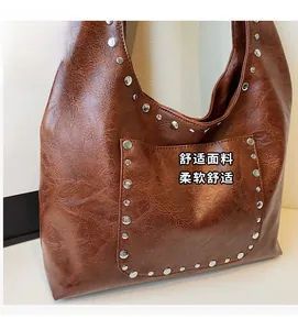 Détail du sac à bandoulière marron vintage avec rivets argentés et texture cuir huilé