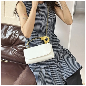 Détail d'un sac bandoulière blanc avec poignée en épingle à nourrice dorée et chaîne chic