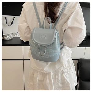 Close-up of light blue denim backpack with chain detail and shimmering glitter texture