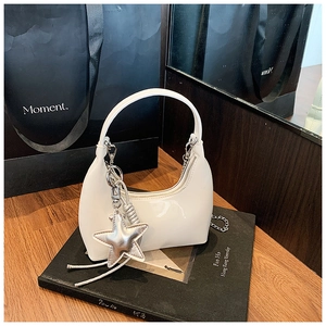 Detail of white patent leather hobo bag with glossy finish and silver star charm