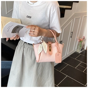 Gros plan du sac à main tissé rose avec fermoir en métal porté par le mannequin