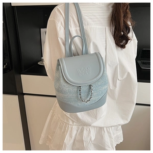 Detail of light blue textured tweed backpack with metal chain and leather flap