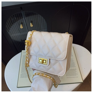 Détail de la texture matelassée blanche et du fermoir doré en métal sur le petit sac