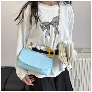 Détail du sac en cuir bleu clair avec poignée épingle dorée et bandoulière en chaîne