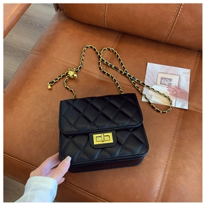 Détail d'un sac bandoulière en cuir matelassé noir avec fermoir doré et chaîne