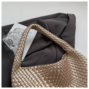 Close-up of woven champagne gold hobo bag texture on elegant grey blazer suit fabric