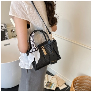 Détail d'un sac porté épaule noir tissé avec foulard en soie et serrure en métal