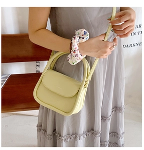 Detail of light yellow PU leather crossbody bag featuring top handle and adjustable strap