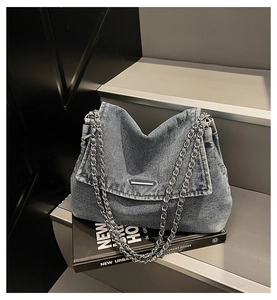 Detail view of washed denim tote bag with thick silver chain and metal clasp closure
