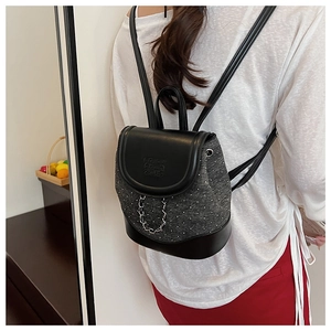 Detail of a chic leather and fabric mini backpack with metallic chain on model