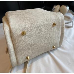 Detail of warm white lychee leather bucket bag with four golden protective metal feet