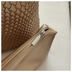 Detail of champagne gold woven texture with smooth metal zipper closure on luxury handbag