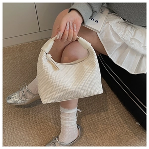 Detail view of a white woven crescent hobo bag with a zipper held by a model