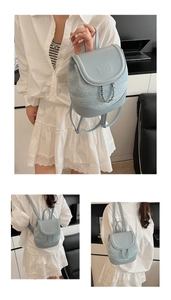 Detail of light blue denim and leather mini backpack with metal studs and chain strap