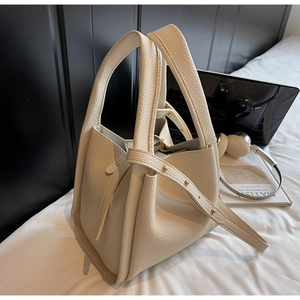 Detail of off-white lychee pattern bucket bag with gold studs and adjustable strap