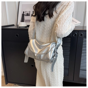 Détail d'un sac bandoulière argenté avec texture plissée et chaîne métallique élégante
